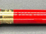 a red pen sitting on a table with a gold trim