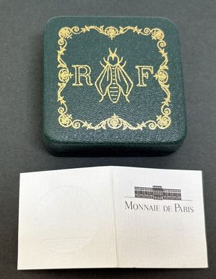 un gros plan sur un livre orné d'une abeille, à côté d'une carte de visite