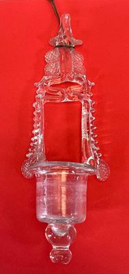 un bougeoir en verre accroché à un mur rouge