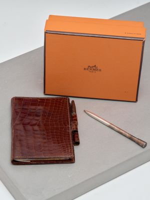 brown leather wallet and pen sitting on top of a table next to a box