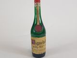 une petite bouteille d'alcool posée sur une surface blanche, avec un bouchon rouge