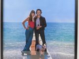 a picture of a man and a woman standing on a pier with a dog