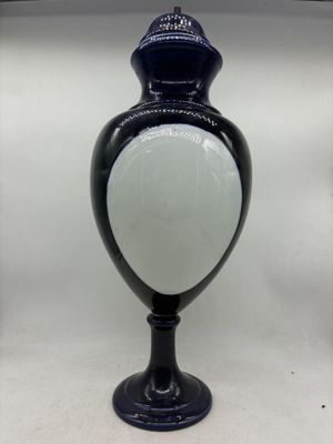un vase noir et blanc avec un couvercle blanc posé sur une table