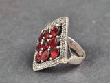 un gros plan d'une bague en argent sertie de pierres rouges