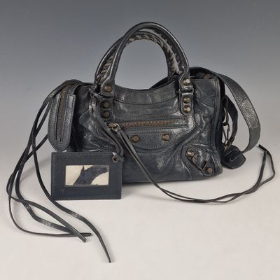 a black purse with a tag attached to it sitting on a table