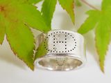 a close up of a silver ring with a leaf in the background