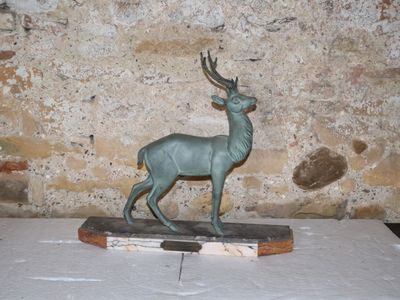 une statue représentant un cerf debout sur un socle en bois