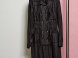 un manteau noir accroché à un porte-vêtements près d'un mur rose et blanc