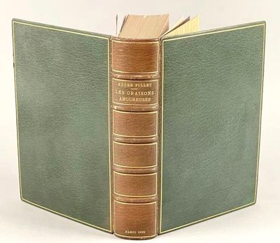 un vieux livre à la couverture verte est ouvert sur une surface blanche