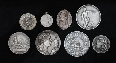 six médailles d'argent de différentes tailles et formes sur fond noir