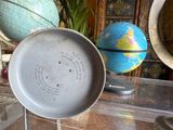 a pan sitting on top of a table with a globe in the background