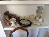 a white shelf with candles, plates, and other items on it