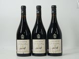 trois bouteilles de vin posées sur une table blanche