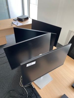 trois écrans d'ordinateur posés sur un bureau dans un bureau