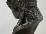 an antique bronze bust of a man with a hat on top of a table