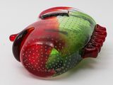 a red and green frog figurine sitting on a white surface