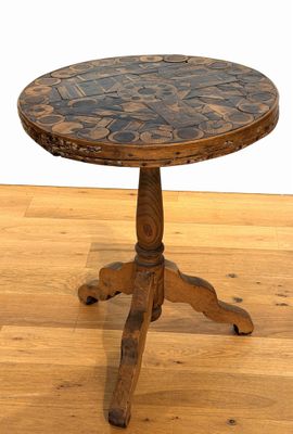 une petite table en bois avec un plateau en faïence, posée sur un parquet