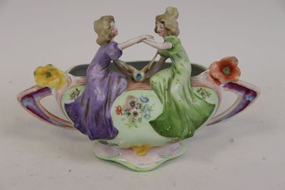deux figurines représentant deux femmes assises dans un vase