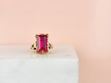 a close up of a pink tourmaline ring sitting on a white block