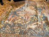 une très grande tapisserie posée à même le sol, autour de laquelle se tiennent des personnes