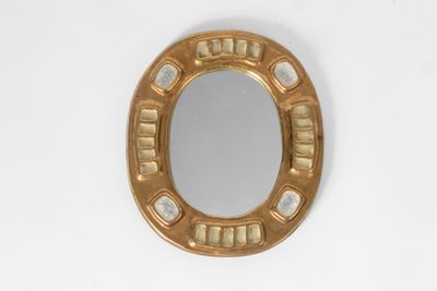 a gold mirror on a white wall with a white background