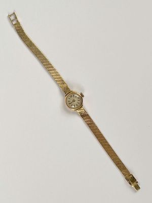 une montre en or sur une surface blanche avec un fond blanc