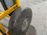 tire of a yellow hand truck with a black tire on it