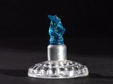 un gros plan d'une petite figurine en verre posée sur une surface noire