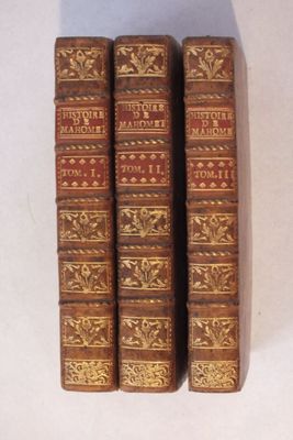 trois vieux livres posés l'un sur l'autre sur une table