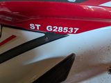 a close up of a red and white motorcycle parked in a garage