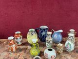 de nombreux vases de toutes sortes posés sur une table, avec un mur rouge en arrière-plan