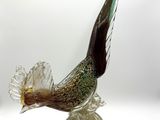 a glass bird that is sitting on a shell