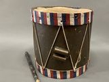 a small drum with a wooden stick in front of it