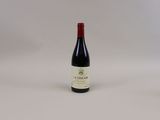 une bouteille de vin rouge posée sur une table blanche