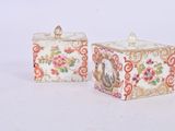 pair of chinese porcelain boxes with floral designs on them on a white surface