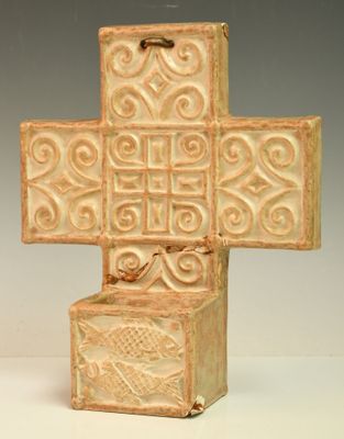 une petite croix en céramique ornée d'un motif décoratif