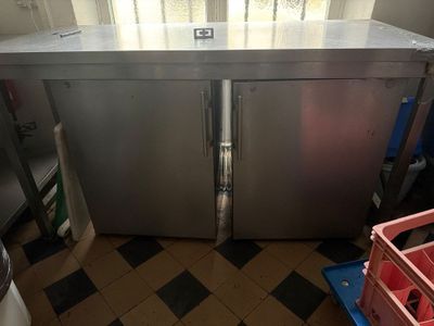 un réfrigérateur en acier inoxydable dans une cuisine au sol en damier