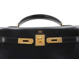 a black leather bag with gold hardware on the handle