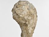 a stone sculpture of a head on a white surface