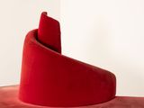 a red chair that has a curved seat on it