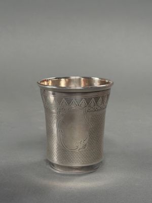 une coupe ancienne en argent, ornée d'un motif sur le bord, sur fond gris
