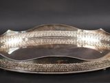 une assiette ancienne en argent aux bords incurvés, sur fond noir
