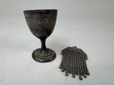 a silver cup and a chain bracelet on a table