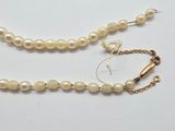 a close up of a necklace with pearls on a white surface