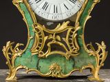 a green and gold clock with roman numerals on it