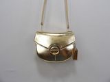 gold purse with tassel hanging on a white wall