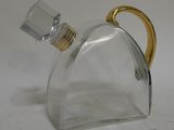 a clear glass bottle with a gold handle on a table