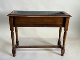 une vieille table en bois avec un plateau en verre, posée sur un plan de travail blanc