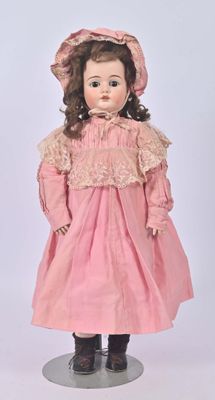 an old fashioned doll with a pink dress and hat on a stand