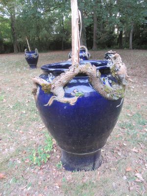 un grand vase bleu orné d'un dragon, posé dans l'herbe